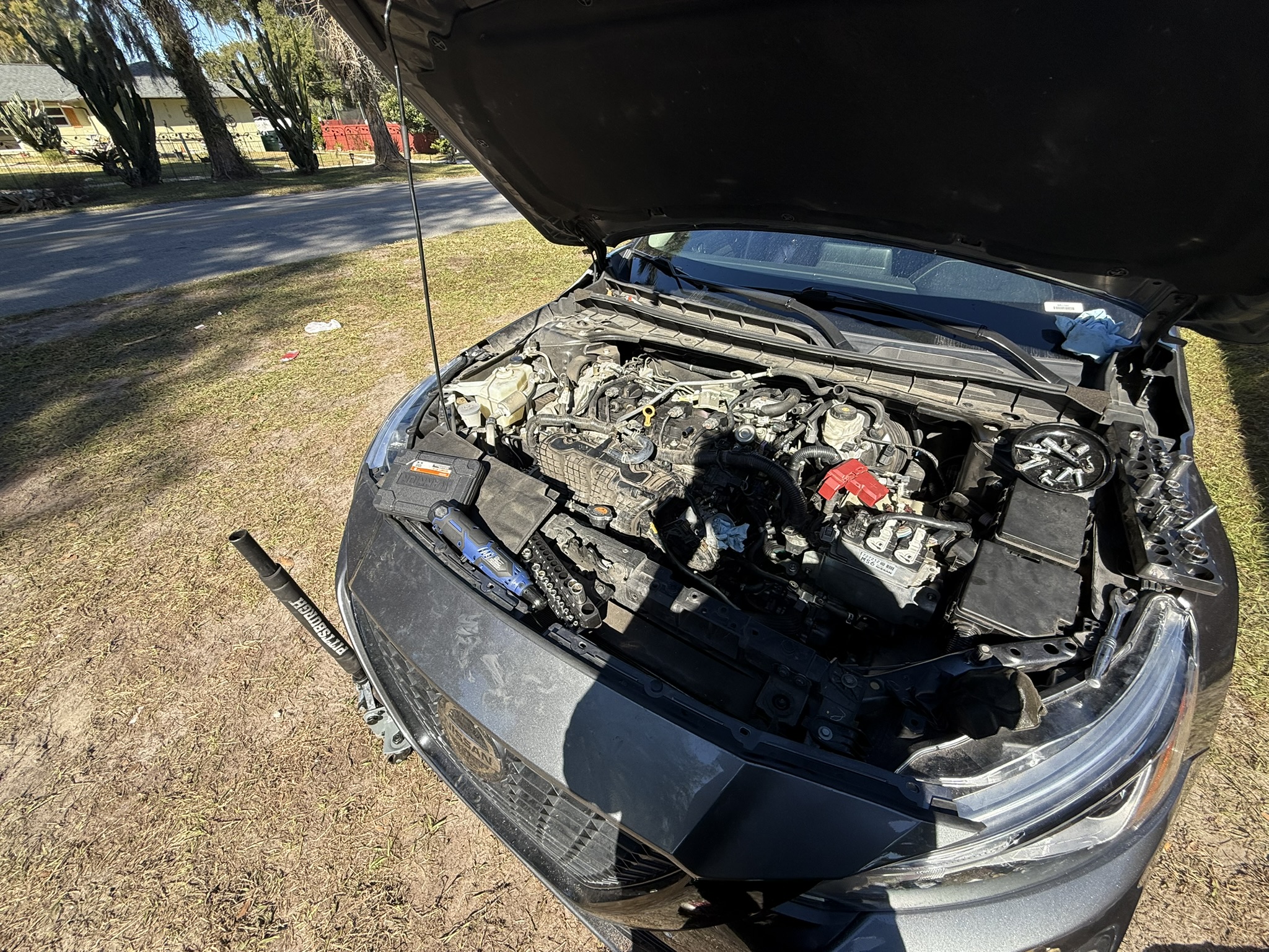 Mobile mechanic working on an engine bay outdoors