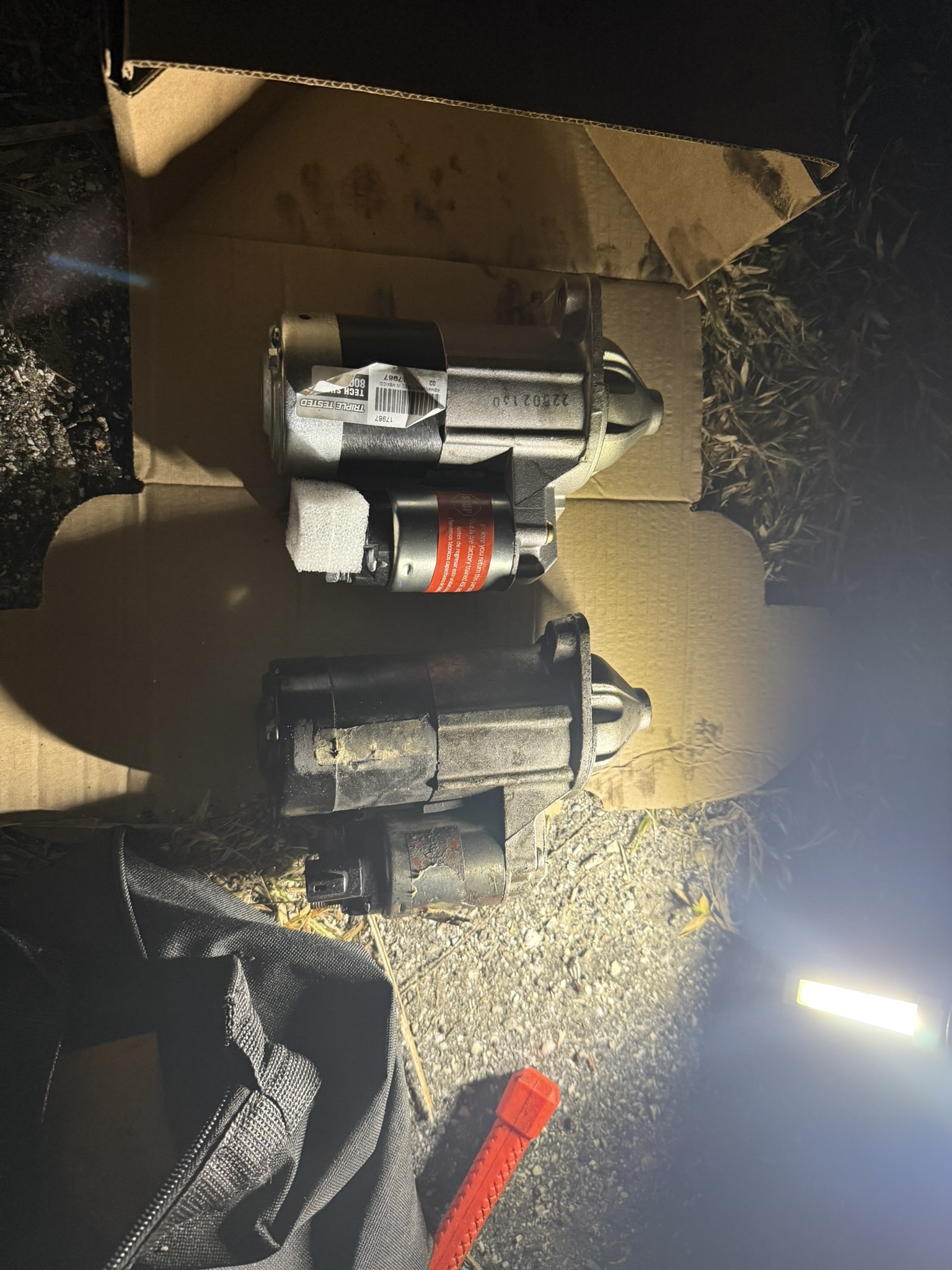 Starter replacement parts laid out during night repair